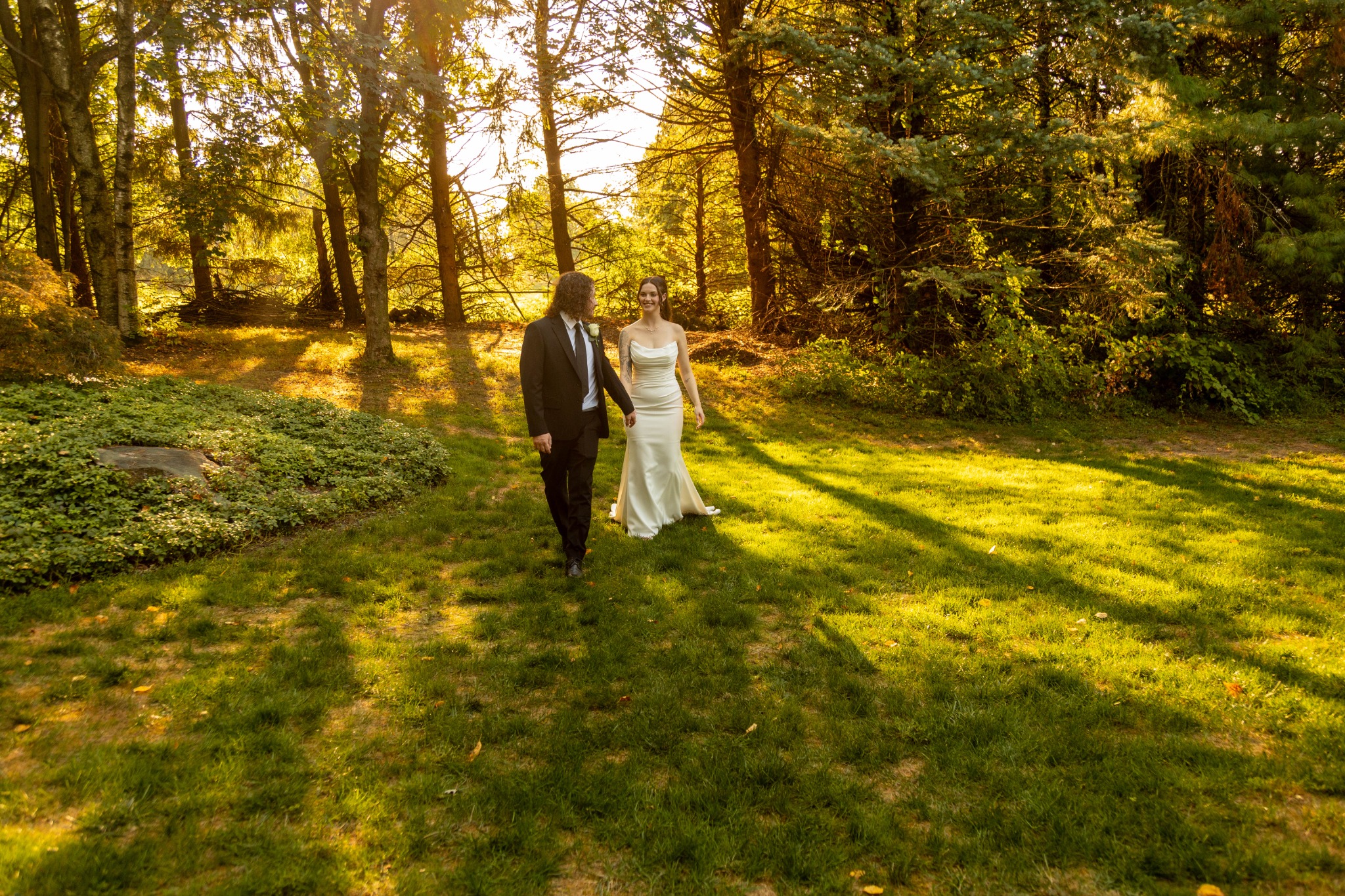 Bride and groom walking together through golden light photographed by MAC Photography